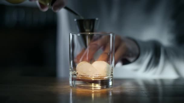 Barkeeper gießt Whisky in die Jigger und dann in das Glas mit Eis, die Herstellung von Alkohol trinken, Cocktail in der Bar, Barkeeper bei der Arbeit, 4k uhd 60p prores hq 422 — Stockvideo