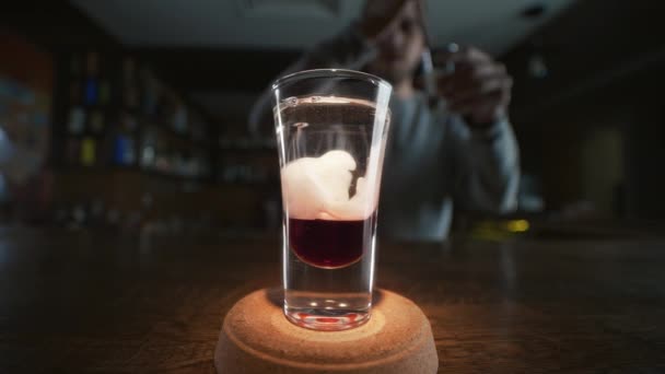 Ο μπάρμαν προσθέτει κλαψούρισμα σε επίπεδα με κόκκινο λικέρ και τζιν σε αργή κίνηση, κάνοντας κοκτέιλ σε ένα μπαρ, ποτό αλκοόλ, μπαρ πάρτι, 4K UHD 60p βίντεο στο ProRes HQ 422 — Αρχείο Βίντεο