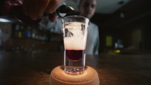 Ο μπάρμαν προσθέτει κλαψούρισμα σε επίπεδα με κόκκινο λικέρ και τζιν σε αργή κίνηση, κάνοντας κοκτέιλ σε ένα μπαρ, ποτό αλκοόλ, μπαρ πάρτι, 4K UHD 60p βίντεο στο ProRes HQ 422 — Αρχείο Βίντεο