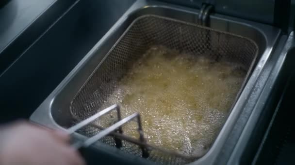 Шеф-повар кладет сырой картофель в кипящее масло для приготовления картошки фри в замедленной съемке, делает картофель фри в ресторане быстрого питания, приготовление картошки, хрустящая картошка фри, 4k UHD 60p Прорес Штаб-квартира 422 — стоковое видео