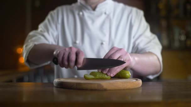 Le cuisinier coupe le cornichon sur la planche en bois dans un bar au ralenti, cuisson burger et salade, nourriture végétarienne et repas, 4k UHD 60p Prores HQ 422 — Video