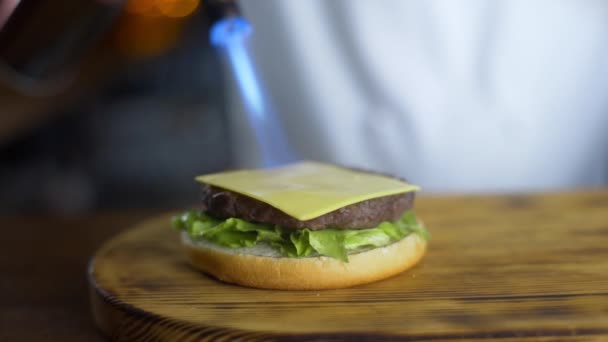 Şef restoranda burger yapma sürecinde pirişlet üzerinde gaz brülör yardımı ile peynir erir, fast food pişirme, hamburger yapma, 4k Uhd 60p Prores Hq 422 — Stok video