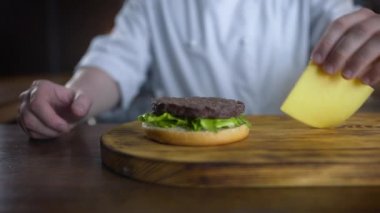 Şef burger dilimlenmiş çedar peyniri ekler ve pirişlet üzerine koyar, yavaş hareket burger pişirme, fast food restoran, 4k Uhd 60p Prores Hq 422