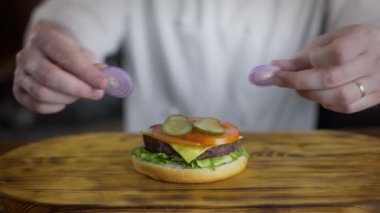 Şef burger pişirir ve içine kırmızı soğan halkaları koyar, fast food restoranda hamburger yapma, 4k Uhd 60p Prores Hq 422
