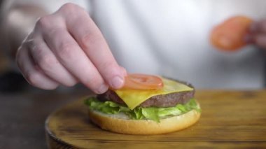 Şef burger pişirir ve içine taze dilimlenmiş domates koyar, fast food restoranda burger yapma, 4k Uhd 60p Prores Hq 422
