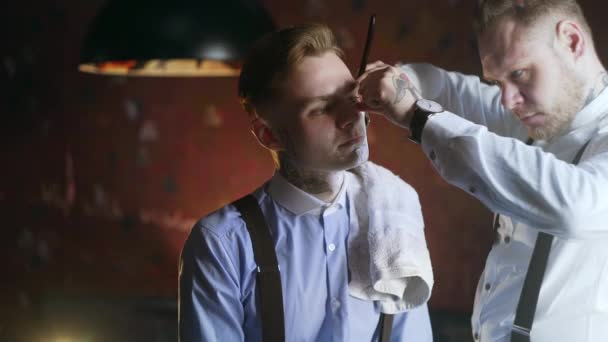Татуированный парикмахер бреет своего татуированного клиента с бритвой, парикмахерская в стиле 30-х годов мафия, бритья салон, 4k UHD 60p Прорес HQ 422 — стоковое видео