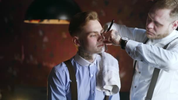 Getatoeëerde Kapper scheert zijn getatoeëerde cliënt met straight razor, Barber Shop in 30s maffia stijl, scheren salon, 4k UHD 60p ProRes HQ 422 — Stockvideo