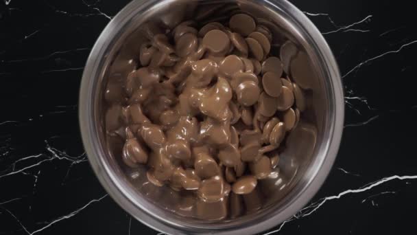 Οι σταγόνες σοκολάτας λιώνουν σε πραγματικό χρόνο στο σιδερένιο μπολ, φτιάχνοντας ερημιές σοκολάτας και γλυκά, είχαν κατασκευασμένη σοκολάτα, σοκολατοποιημένη στην εργασία, Full HD ProRes HQ 422 αργή κίνηση — Αρχείο Βίντεο
