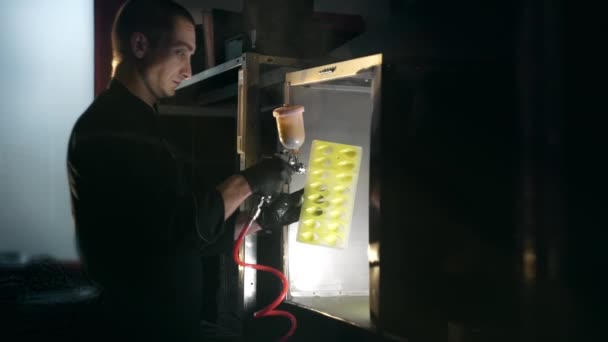 L'homme peint le détail en couleur jaune par pistolet de pulvérisation dans le capot d'échappement, colorant d'usine, travaillant avec pistolet de pulvérisation à l'intérieur, Full HD Prores HQ 422 au ralenti — Video