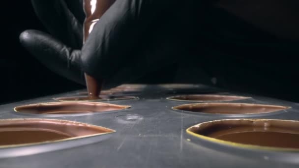 Chocolatier remplit les moules de chocolat avec remplissage de chocolat liquide pour les bonbons pralinés, fabrication de bonbons et de barres de chocolat à la main, full hd Prores HQ 422 — Video