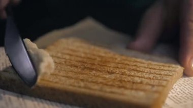 Yakın çekim: aşçı çıtır kavrulmuş tost ekmeği üzerine bıçakla tereyağı yayılır, sandviç yapma, ev yapımı fast food, evde yemek, aperatifler, Full Hd Prores 422 Hq