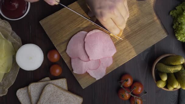 Gros plan vidéo de jambon naturel savoureux est tranché par couteau tranchant sur la planche en bois, viande fumée saccadée, fabrication du sandwich avec du jambon tranché, cuisson de la viande, à la boucherie, Full HD Prores HQ 422 — Video