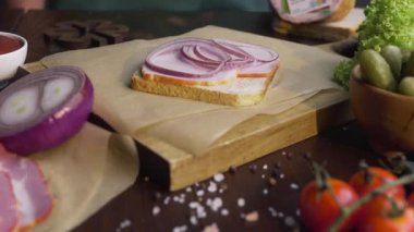 Cook, mutfakta, et pişirme, mutfak, Full HD ProRes HQ 422 fastfood yapımında, ışık ışınında ahşap tahta üzerinde jambon ve sebzeler ile sandviç için dilimlenmiş domates ekler