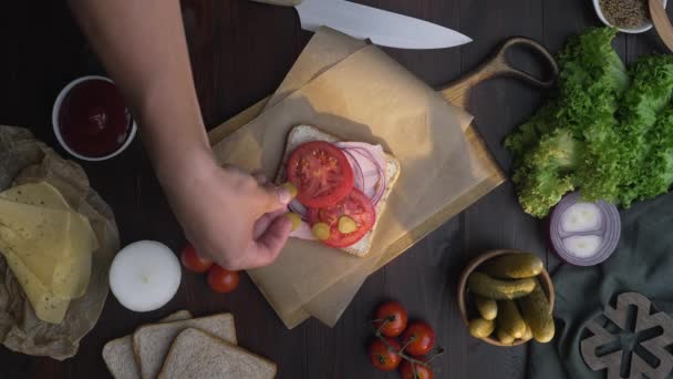 Flat feküdt szakácsok kezét egészíti szeletelt paradicsom a szendvicset sonkával és zöldségekkel a fából készült hajón a fénysugár, hogy a gyorsétterem otthon, húst főzés, a konyhában, Full HD