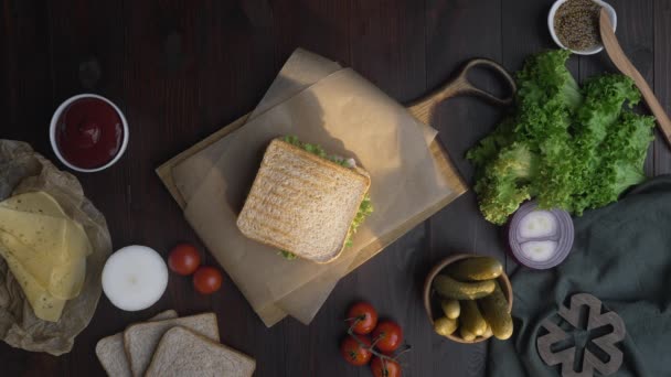 Płaski strzał lay: człowiek kawałki kanapkę klubu w połowie ostrym nożem na drewnianej płycie w kuchni, co Fastfood w domu, kucharz jest gotowanie kanapkę, Full HD ProRes HQ 422 — Wideo stockowe