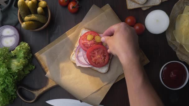 Flat Lay av kockar hand lägger skivad tomat till smörgås med skinka och grönsaker på trä ombord i ljusstrålen, gör av Fastfood hemma, kött matlagning, i köket, 1080p ProRes — Stockvideo