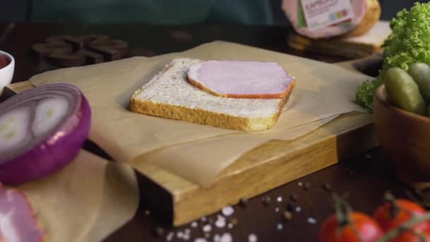 Zbliżenie wideo dokonywania kanapkę z plasterkami szynki i warzyw, szef kuchni dodaje wędzoną szynkę do kanapek, Dokonywanie Fastfood w domu, gotowanie mięsa, w kuchni, Full HD ProRes HQ 422 — Wideo stockowe