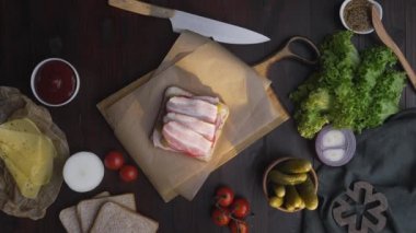 Düz dilimlenmiş pastırma ve salata ile sandviç yapma yatıyordu, Şef ahşap tahta üzerinde sandviç salata ekler, evde fastfood yapımı, et pişirme, mutfakta, Full HD ProRes HQ 422