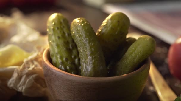 Pickles zijn in de houten kom op de keuken tafel in een bundel van zonsondergang licht, ingeblikte groenten, ingrediënten voor het koken, ingeblikte komkommers, Full HD ProRes 422 HQ — Stockvideo