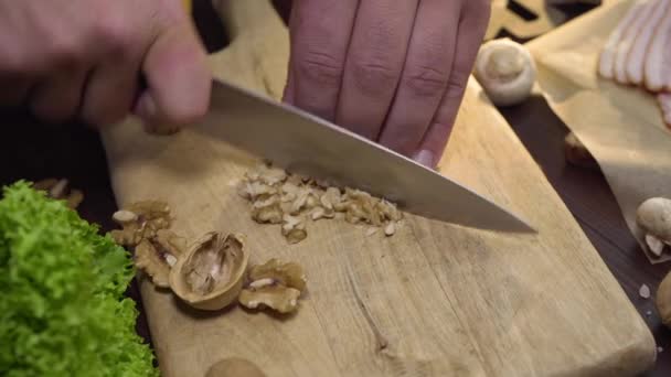 Закрыть видео: шеф-повар режет грецкие орехи на деревянной доске, готовит салат, витаминную пищу, измельчает орехи, ингредиенты для приготовления пищи, Full HD Prores 422 HQ — стоковое видео