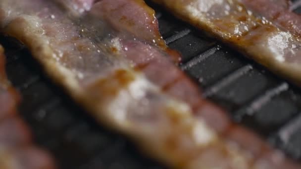 Macro shot de morceaux de bacon rôtis sur le gril chaud, slow motion shot de bacon grillé, tranches de viande sur la poêle, cuisson de la viande, nourriture délicieuse malsaine, Full HD Prores 422 HQ — Video