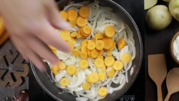 Vídeo plano: el chef agrega zanahoria picada a la cebolla en la sartén caliente y la agita con espátula de cocina de madera, mesa de guiso de cocina, cebolla frita y zanahoria, verduras blanch, Full HD Prores 422 HQ — Vídeo de stock