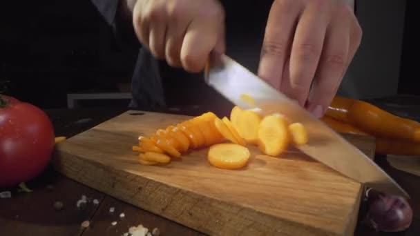 Ζουμ του κοπής ωμό καρότο στον ξύλινο πίνακα, κοπή λαχανικών, τεμαχισμό του φαγητού, κομμένα σε κύκλους, άλεση τα λαχανικά, μαγείρεμα με καρότο, ώριμες ρίζες, Full HD ProRes 422 HQ — Αρχείο Βίντεο