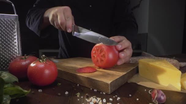Koch schneidet reife rote Tomaten in einem Kreis auf dem Holzbrett mit dem scharfen Messer, Zutaten für Gemüsesalat, Kochketchup-Sauce, Full HD prores 422 hq — Stockvideo