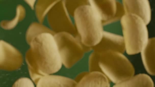 Fallende knusprige goldene Kartoffelchips in Zeitlupe auf grünem Hintergrund, Slow Motion Food, Snacks und Fast Food, 240p full hd 10 bit — Stockvideo