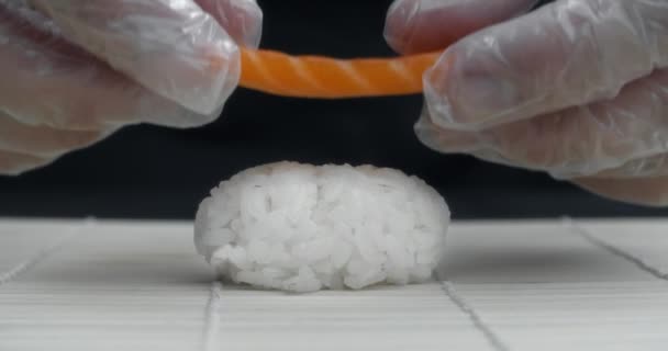 Chef zet zalm slice aan de rijst, waardoor de nigiri in slow motion, koken sushi broodjes, Aziatisch eten met vis en rijst, 4k DCI 60p ProRes HQ 10 bit — Stockvideo