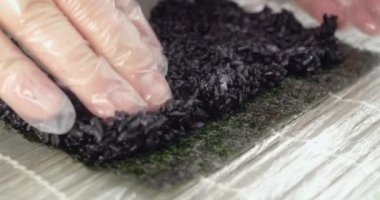 Şef nori siyah pirinç koyar ve yavaş hareket suşi rulo yapar, asya gıda, suşi ve nigiri pişirme, Asya restoran pişirme süreci, 4k Dci 60p Prores 422 Hq 10 bit