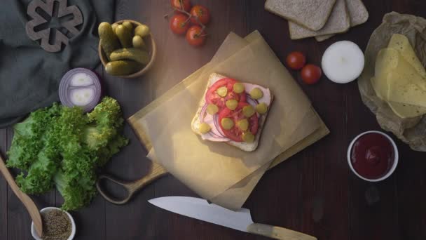 Flat lay van de sandwich met ham en groenten op het houten bord in de lichtstraal, het maken van de fastfood thuis, vlees koken, in de keuken, 4k Uhd Prores Hq 422 — Stockvideo