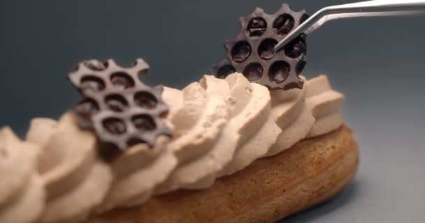 Confectioner finishes eclair with pieces of chocolate and puts them on cream by small tweezer, dessert in cafe, stuffing for eclairs, choux pastry, 4k DCI 120fps Prores 422 HQ 10 bit — Stock Video