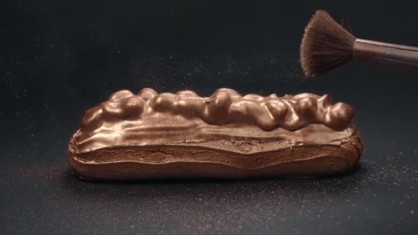 Eclair em esmalte de chocolate com amêndoa é polvilhado com pó de ouro, confeiteiro no trabalho, fazendo de sobremesa dourada lindo, Full HD 120 fps Prores 422 HQ 10 bit — Vídeo de Stock