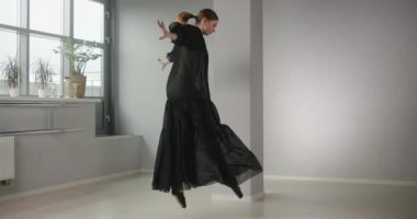 Uzun siyah elbiseli çekici bayan dansçı yavaş çekimde atlıyor, bale egzersizleri ve numaralar yapıyor, bale provası, sahne kostümünde dans adımları, dans stüdyosu dersi, 4k