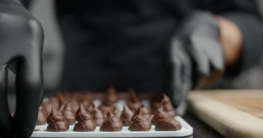 Şefin siyah eldivenli çikolatacısı yavaş çekimde kendi kendine pişmiş çikolatalardan küçük şekerlemeler yapıyor, yer mantarlarını yapıyor, çikolata ve kakaodan tatlı tatlılar pişiriyor, şeker yapıyor, 4k DCI 120