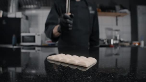 Chef Chocolatier zertrümmert die weiße Schokoriegel per Küchenhammer auf dem Marmortisch in Zeitlupe, Rohstoffe für die Herstellung von Süßigkeiten und Schokolade, Konditor bei der Arbeit, 1080p 240fps Prores HQ — Stockvideo