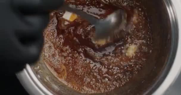 Masa başı ağır çekim videosu: siyah eldivenli şekerlemeci kaynayan şekere tereyağı ekler, şef sıcak karamel yapar, pasta doldurur, 4k 60fps Prores HQ 10 bit — Stok video