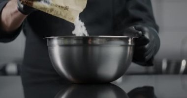 Siyah eldivenli şekerlemeci şeker tozunu ağır çekimde metal kaseye boşaltır, çikolatalı şeker ve şeker yapar, hamur tatlısı, yemek videosu, 4k 120fps Prores