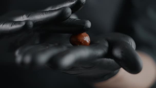 黒手袋のシェフショコラティエは、ゆっくりとした動きで自己調理されたチョコレートから小さなキャンディーをロールアップし、トリュフを作り、チョコレートとココアから甘いデザートを調理し、フルHD 240fpsで証明HQ — ストック動画