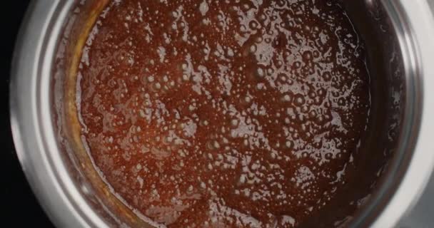 Asztali lassított felvétel: Az olvasztott cukor forr a forró tűzhelyen lévő fémtálban, forró sós karamellát készítve, főzőcskézve a tortához, desszertet és cukorkát készítve, 4k 60fps Prores HQ 10 bit — Stock videók