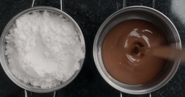 Tiro de mesa: el chocolatero del chef derrama chocolate con leche derretida al tazón de metal, el confitero utiliza chocolate caliente en dulces de cocina y barras de chocolate, cocinando los postres, 4k DCI 120 fps HQ de Prores — Vídeo de stock