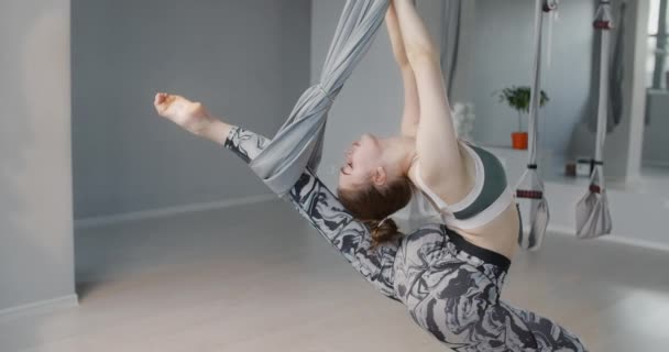 Giovane ginnasta donna si allunga e gira sull'amaca yoga al rallentatore, persona fa esercizi fisici, stretching e ginnastica, 4k DCI 60p Prores HQ 10 bit — Video Stock