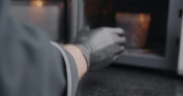 Kocken i svarta handskar tar kan från mikrovågsugn i slow motion, matlagning i mikrovågsugn, uppvärmning av halvfabrikat, varm kokande mat, 4k DCI 120 fps Prores HQ 10 bit — Stockvideo