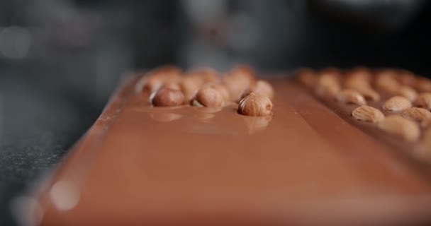 Кондитер добавляет жареные орехи в горячий шоколадный батончик ручной работы, искусство шоколада, приготовление десертов из шоколада и коки, изготовление батончиков, сладких десертов, 4k 120 fps Prores HQ — стоковое видео