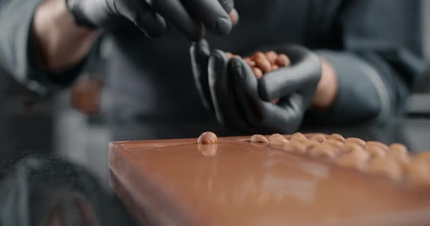 Confectioner adds roasted hazelnuts to the hot handmade chocolate bar, the art of chocolate, cooking desserts from chocolate and cocoa, making bars, sweet desserts, 4k 120 fps Prores HQ — Stock Video