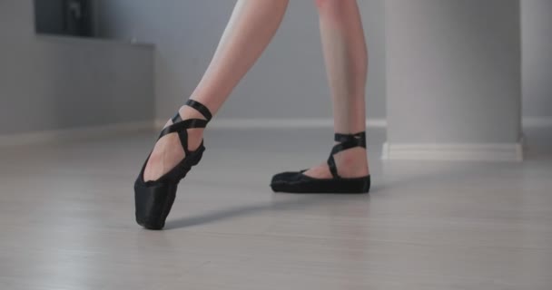 Jonge danseres in doet ballet oefeningen door haar been in zwarte puntschoenen, ballet repetitie, ballerina doet danspassen, dansles, 4k 60p Prores HQ — Stockvideo