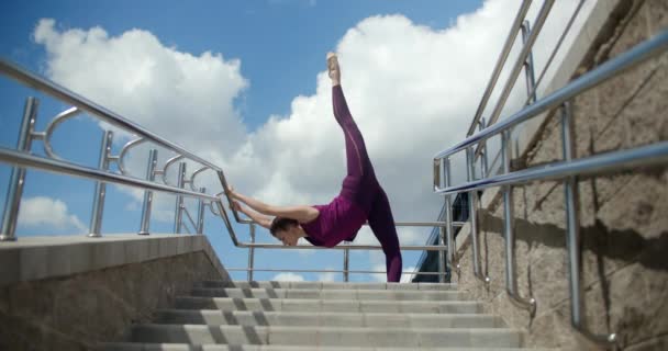 Atletik kadın sokak merdivenlerinin tırabzanlarında esneme egzersizleri yapıyor, şehir ortamında fitness, yoga sınıfı açık havada, şehirde fiziksel egzersiz, 4k 120p Prores HQ — Stok video
