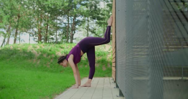 Femme athlétique fait de la ficelle verticale au mur, des exercices d'étirement dans l'environnement urbain, cours de yoga à l'extérieur, l'entraînement physique et de remise en forme dans la ville, 4k 120p Prores HQ — Video