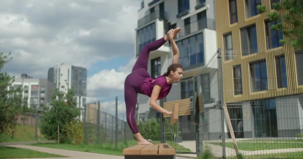 Femme athlétique fait de la ficelle verticale debout sur le banc, des exercices d'étirement dans l'environnement urbain, cours de yoga en plein air, entraînement physique et de remise en forme dans la ville, 4k 120p Prores HQ — Video